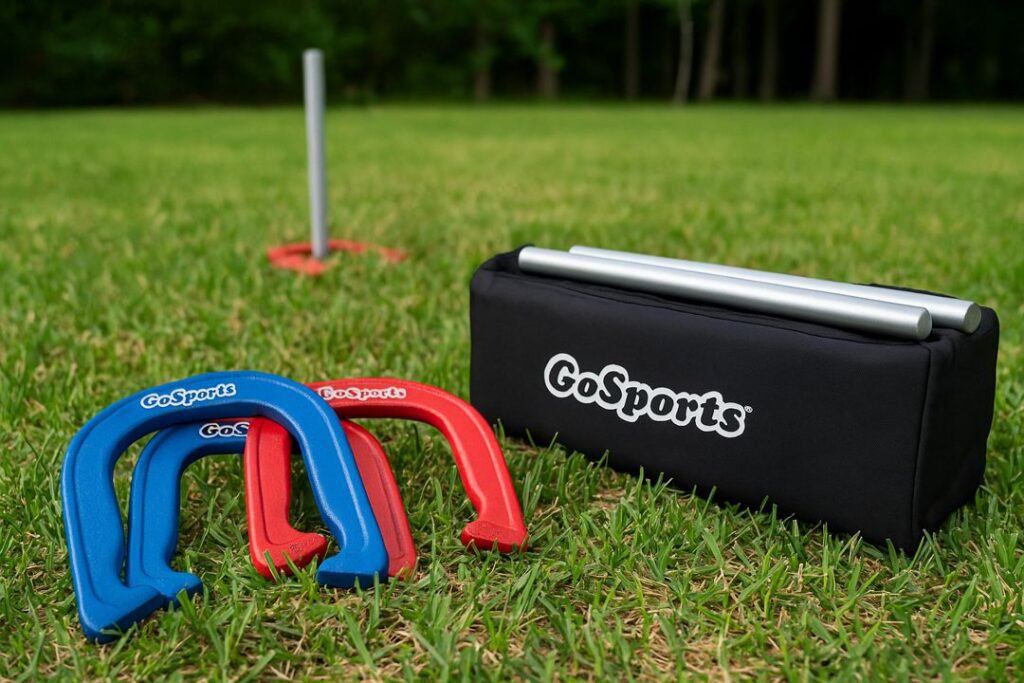 Red and blue steel horseshoes and stakes arranged on grass beside a carrying case during a sunny backyard horseshoe game.