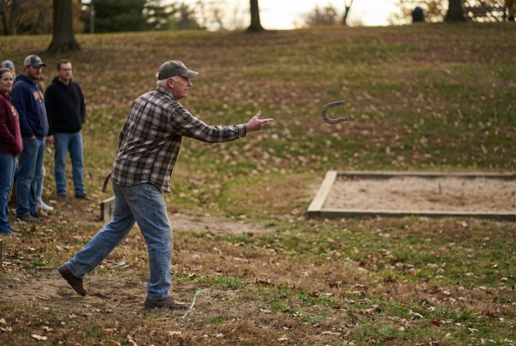 Horseshoe player pitching uphill on uneven backyard court