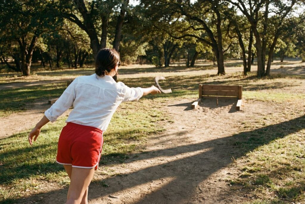 Horseshoe player releasing the shoe with calm, repeatable tempo and relaxed arm motion toward the stake